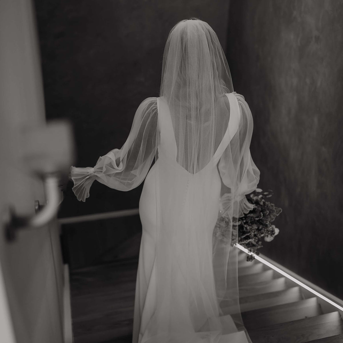 Black and white photo of bride wearing a veil and holding a bouquet
