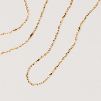 Gold chain necklace on a light gray background