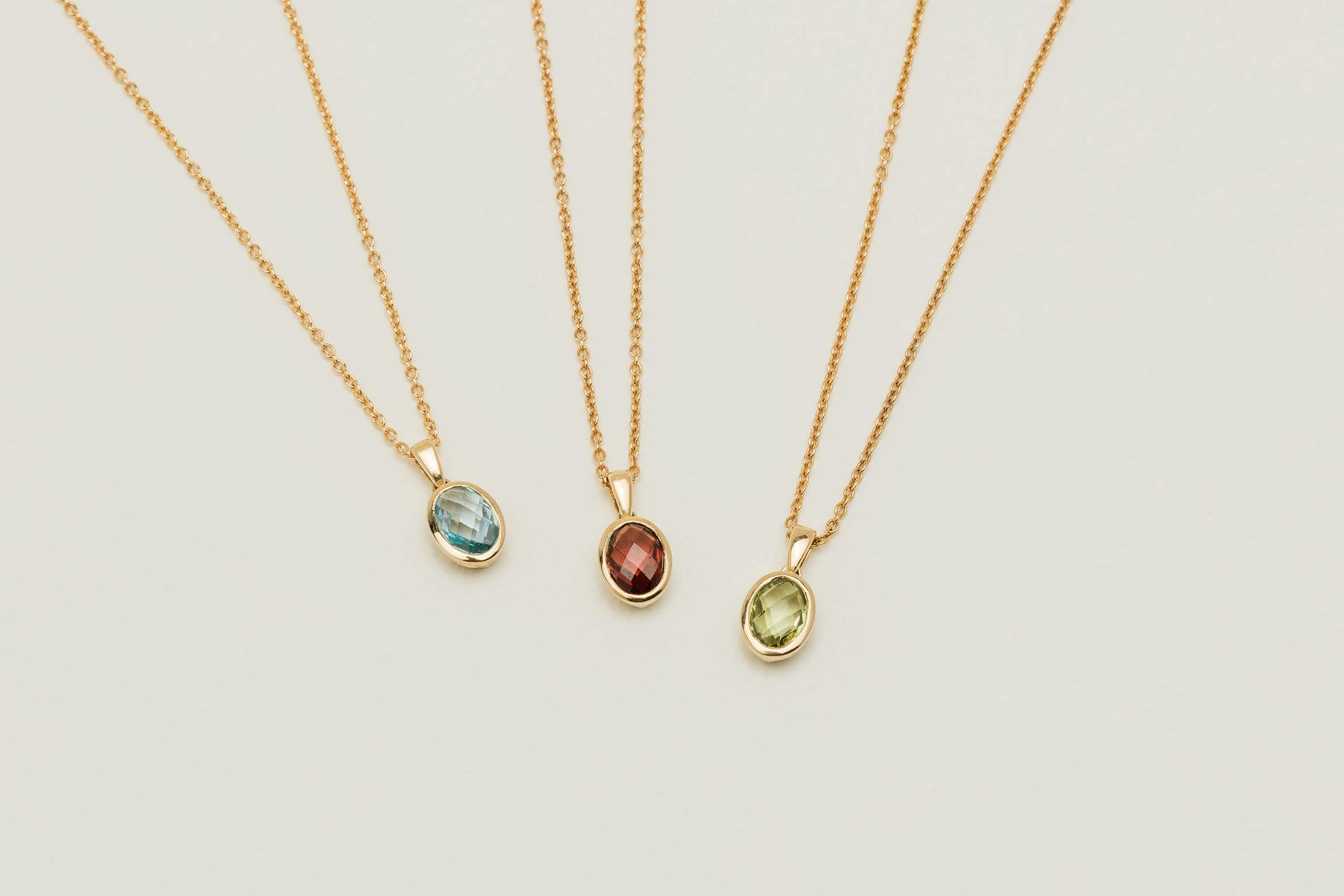 Three coloured gemstone Iris Pendants on neutral background