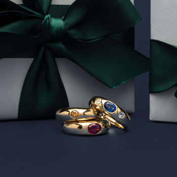 Coloured stone Kylie Rings on navy blue background with wrapped Walker & Hall gift boxes