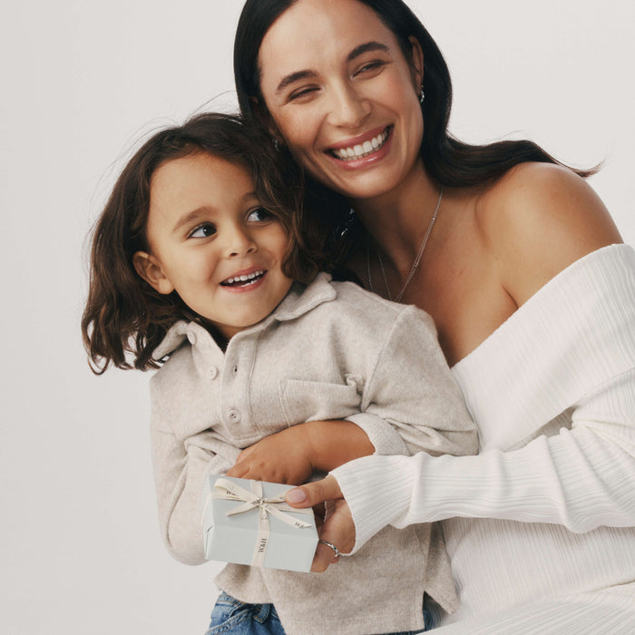 Mother and son embracing and holding a wrapped Walker & Hall giftbox