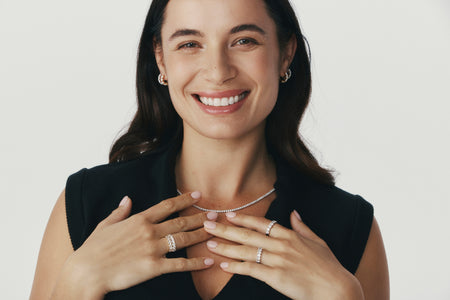 Model smiling wearing diamond rings, earrings and necklace