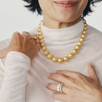 Close up of woman wearing a golden pearl necklace and golden pearl ring