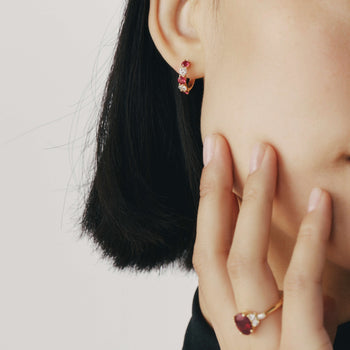 Close up of a woman wearing a ruby and diamond ring and ruby and diamond earrings