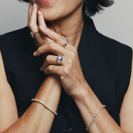 Close-up of a woman wearing sapphire and diamond rings and bracelets