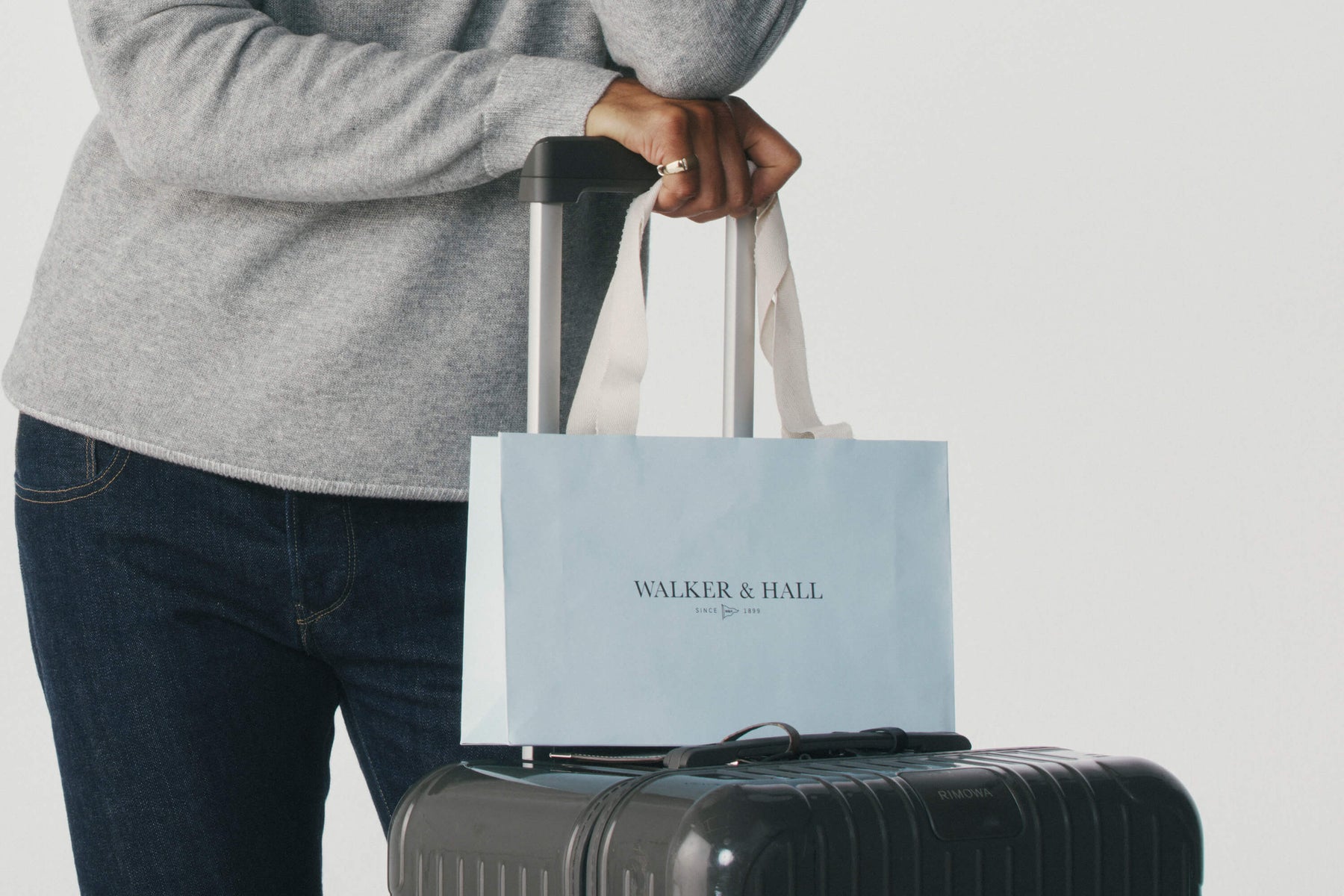 Model holding a Walker & Hall bag on top of a suitcase