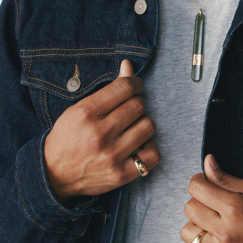 Close-up of a person wearing a gold signet ring and denim jacket.